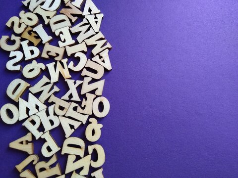 wooden letters of the alphabet scattered on a purple background with space for text. High quality photo