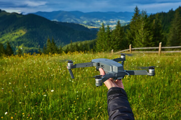 Start the drone, launching from hands. Modern small copter with camera in user hand, against sky.