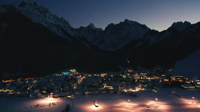 Kranjska gora at winter at night with city lights and snow. Drone shot, aerial view.