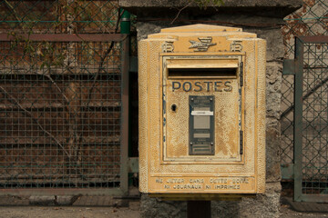 Andorra - Santa Coloma - the old yellow french post box set against a de-focused old green fence...