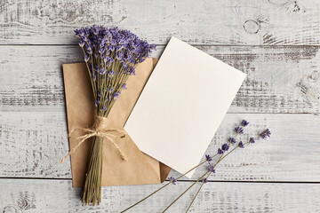 Flat lay with empty greeting card with envelope and dry lavender flowers on wooden background