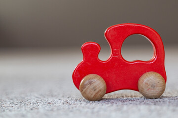 Closeup of red wooden toy car on carpet