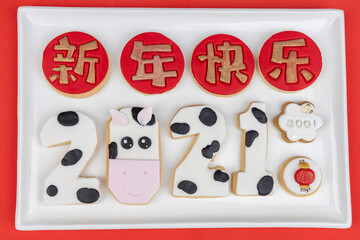 Chinese New Year 2021 themed cookies displayed on a white plate on a red table cloth