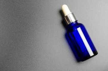 Blue bottle on a black background. Serum in a glass bottle. Organic natural oils