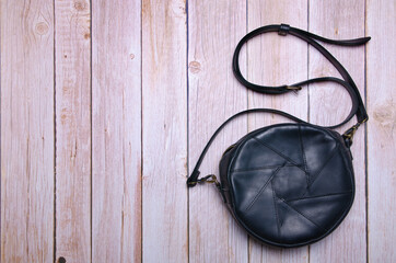 Fototapeta na wymiar Woman black leather bag fashion on wooden background. Top view with copy space