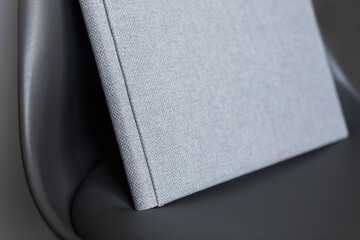 family photo book. stylish Photo album on chair . grey photobook with  leather cover. Beautiful photoalbum with hard  fabric cover on background . Pastel wedding photo album with copy space for text.