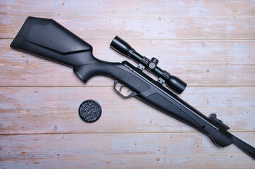 pneumatic rifle on wooden background. Top view with copy space