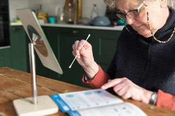 A senior woman check the instructions for a home testing coronavirus swab check