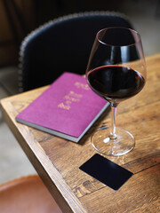 glass of wine on wooden table with wine card menu