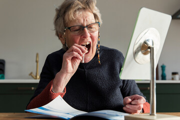 A senior woman takes a mouth sawb at home to check for coronavirus disease