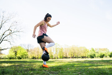 Obraz na płótnie Canvas Young female soccer player practicing on field.