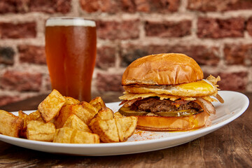 Tasty burger with fried egg and bacon served with potatoes.