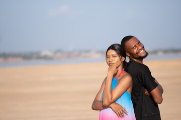 two young africans, couple standing back to back and smiling outdoor