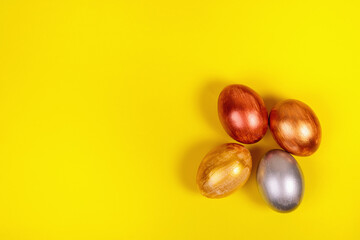 Multi-colored eggs on a uniform yellow background with place for text.