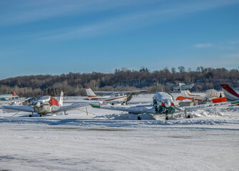 Private aircraft parked on runway tarmac at private airport in winter with snow on ground nobody