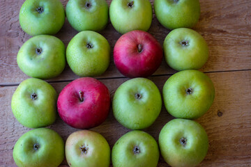 Green and red apples stand on a wooden surface
