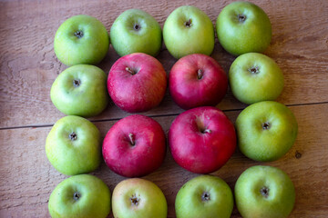 Green and red apples stand on a wooden surface