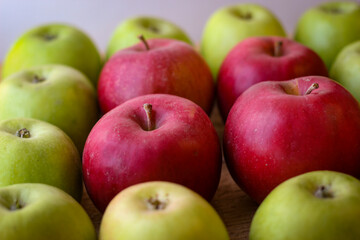 Green and red apples stand on a wooden surface