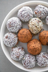 Handmade coconut snow balls made from dates, almond and coconut truffles on grey surface, healthy eating cocept