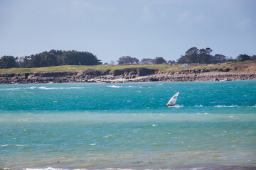 A windsurfer enjoying the beautiful scenery of the coast of Ploudalmezeau, Finistere, Bretagne,...