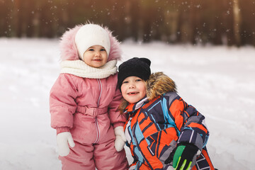 Brother and sister on a walk in a winter park. Happy children in nature