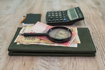 different hryvnia, credit cards, women's wallet, calculator, magnifier on a wooden background.