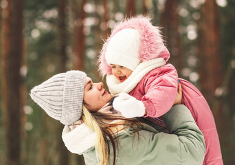 Obraz premium Young mother plays with her little daughter in winter in the park, holds in her arms and circles