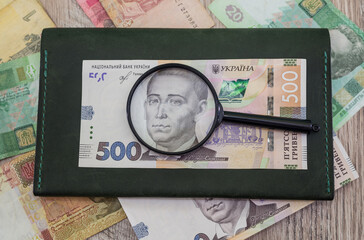 Ukrainian hryvnia with magnifying glass and wallet