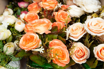 Lot of artificial coral rose flowers on ground. Flowers for sale for Memorial Day