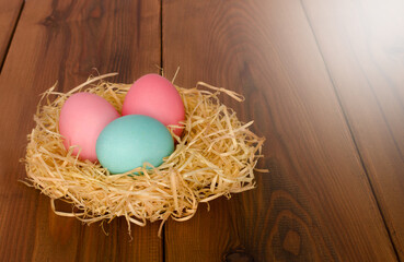 a nest with painted eggs lies on a wooden table