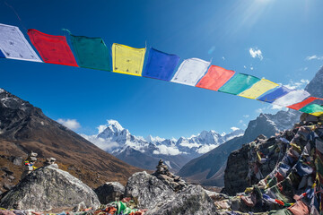 Holy buddhist praying multicolored flags with mantras flapping and waving on the strong wind with valley view and Ama Dablam 6812m peak.Everest Base Camp trekking route near Dughla 4620m.