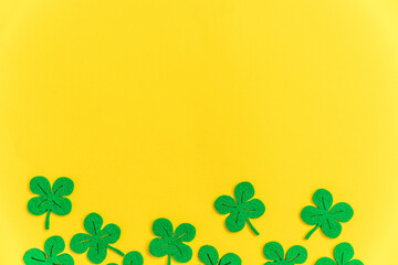 St Patricks Day background. Simply minimal design with green shamrock. Clover leaves isolated on yellow background. Symbol of Ireland. Lucky fortune wish concept. Flat lay top view layout copy space.