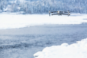 Flying drone against winter background with river and forest