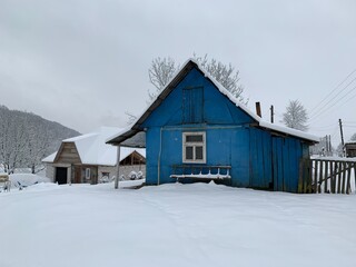 Wooden house in the village in winter. An old wooden building by the forest. Village house in the mountains.