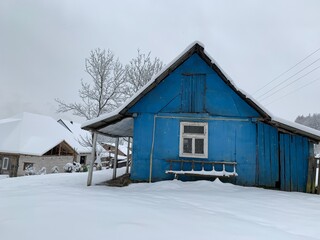 Wooden house in the village in winter. An old wooden building by the forest. Village house in the mountains.