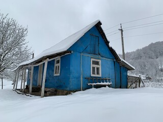 Wooden house in the village in winter. An old wooden building by the forest. Village house in the mountains.