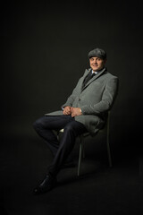 in a coat and a cap a scarf Young male three piece suit confident caucasian fashion, confidence permanent lifestyle. Handsome model, successful smile background black bodybuilder