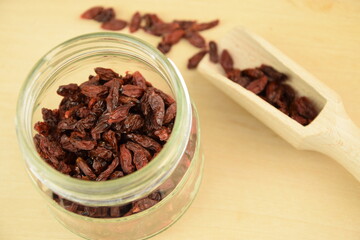 Dried goji berries on jar,  spoon, wooden background, super food, organic healthy fruits
