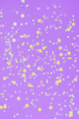 Festive purple background with colorful flowers. Multi-colored small artificial flowers. Flat lay, top view.