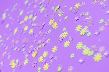 Obraz na płótnie Canvas Festive purple background with colorful flowers. Multi-colored small artificial flowers. Flat lay, top view.