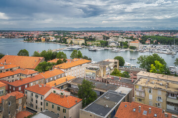 Obraz premium Drone or birds eye view on orange tiled roofs and cityscape of Zadar. Bay or marina with moored yachts and boats, Croatia