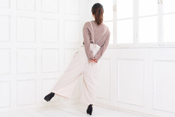 白い部屋に立ってポーズをとる若い女性