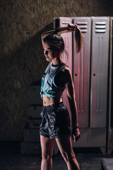 Fototapeta na wymiar young girl stands in an atmospheric fitness room against the background of lockers for changing room