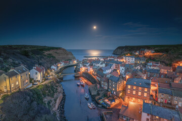 Moonrise over the North Yorkshire fishing village of Staithes. - obrazy, fototapety, plakaty