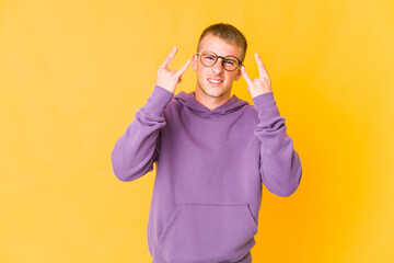 Young caucasian handsome man showing a horns gesture as a revolution concept.