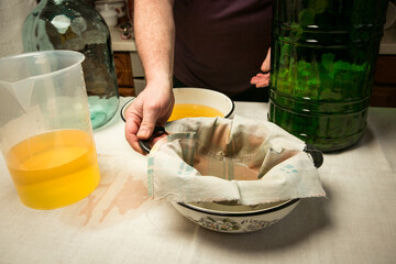 The process of making limoncello lemon liqueur at home. The man drains and strains the alcohol...
