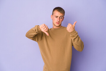 Fototapeta premium Young caucasian handsome man showing thumbs up and thumbs down, difficult choose concept