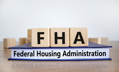 FHA symbol. Wooden blocks and book with words 'FHA federal housing administration'. Beautiful white background, copy space. Business and FHA - federal housing administration concept.