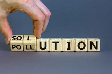The solution to pollution symbol. Male hand flips wooden cubes and changes the word 'pollution' to 'solution'. Beautiful grey background, copy space. Business, ecological and pollution concept.