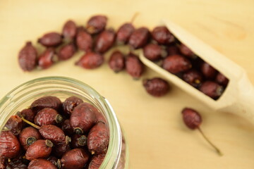 Rose hips, dried wild rose fruits on jar, natural wooden background, super food, healthy fruits, vitamin C and antioxidants resource